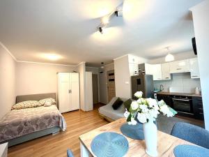 a living room with a bed and a table with a vase of flowers at Studio Zielony Ryneczek in Zamość
