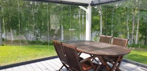 a wooden table and chairs sitting on a screened porch at River landscape close to the centre, Himos 8km in Jämsä