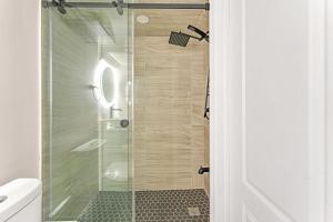 een douche met een glazen deur in een badkamer bij 2 BR ground-level suite in a bungalow with full kitchen, parking, and 20 mins to Downtown in Toronto