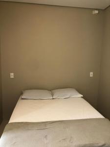 a bed in a room with two pillows on it at Suíte privativa próxima ao Sesc 3 in Bertioga