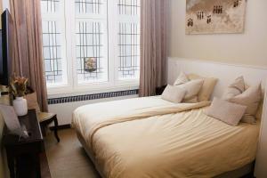 a bedroom with a white bed with two windows at 't Kabinet in Blankenberge