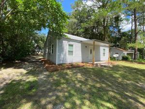 a small white house in the middle of a yard at The Charming Location in Waycross