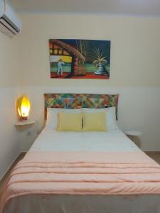 Flores do Riacho- Chalés في ساو ميغيل دوس ميلاجريس: غرفة نوم بها سرير ولوحة على الحائط