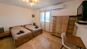 Cette chambre comprend deux lits, une table et une télévision. dans l'établissement Villa Corse, à Folelli