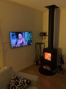 a living room with a fireplace and a flat screen tv at Mysig stuga i Nävesta in Örebro