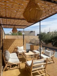a patio with chaises and chairs under a wooden pergola at Villa Luna Marrakech in El Mers