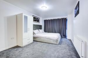 a white bedroom with a bed and a dresser at Newly furnished stunning 2 bedroom flat in Colindale