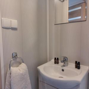 een witte badkamer met een wastafel en een spiegel bij zeeuwse chalet voor 2 personen in Serooskerke +7 foto's