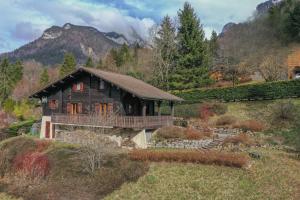 une maison en bois avec une terrasse dans les montagnes dans l'établissement Chalet Paolina proche le Grand Bornand et la Clusaz, à Glières-Val-de-Borne