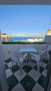 a table and two chairs on a patio with a view of the ocean at Appartement à Tanger Vue Mer in Tangier