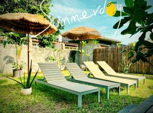a row of lounge chairs with umbrellas in a yard at HomeOne36 后灣灣inn - 勝利星村日式老屋包棟 - in Pingtung City