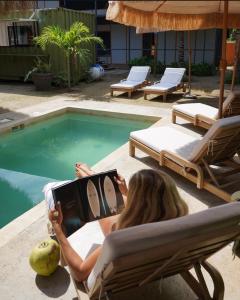 a woman sitting in a chair next to a swimming pool at La Paz Perfecta a Playa Saladita in Temalhuacán
