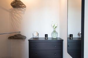 Eine schwarze Kommode mit einer Vase drauf. in der Unterkunft Maricor in South Cerney