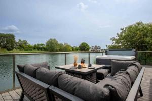 eine Terrasse mit einer Couch und einem Tisch am Wasser in der Unterkunft Maricor in South Cerney
