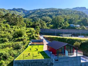ein kleines rotes Haus mit einem Hof mit Gras in der Unterkunft Ginjas Mountain Houses in São Vicente + 3 Fotos