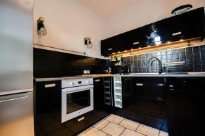 a kitchen with black cabinets and a sink and a stove at Casamea - Apt Spacieux, Clim, Famille & Cabane in Ajaccio
