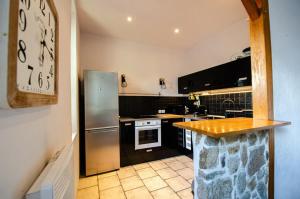 a kitchen with stainless steel appliances and a clock on the wall at Casamea - Apt Spacieux, Clim, Famille & Cabane in Ajaccio