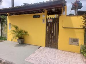 a yellow house with a gate and a plant at Suítes Cantinho do Sossego Ubatuba in Ubatuba