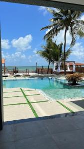 a swimming pool with palm trees and the ocean at Casa de praia Itamaracá - Pontal da Ilha in Itamaracá