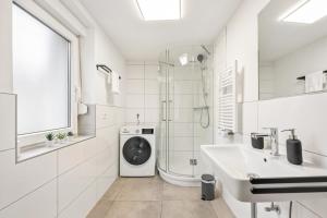 baño blanco con lavadora y lavamanos en Sali Homes Ziegeleihaus, en Heilbronn