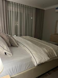 a bed with white sheets and pillows in a bedroom at شقة مفروشة بحي الشراع بالخبر 2 in Al Khobar