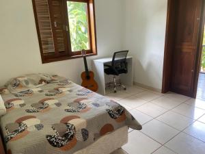 una camera da letto con un letto e una chitarra dentro di Linda casa no centro de Penedo a Itatiaia