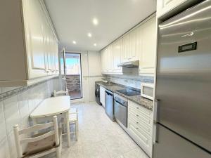 a kitchen with white cabinets and a stainless steel refrigerator at Madrid Luxe Oasis 4 Bedroom with Terrace & Pool in Torrejón de Ardoz