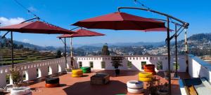 a patio with two red umbrellas and someools at Sunset Valley Holiday Inn in Ooty