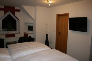 a bedroom with a bed and a flat screen tv at Landgasthaus Hotel Wolters in Kerken
