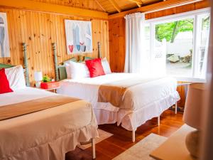 a bedroom with two beds and a window at Cottage 11 - Double Queen Beds plus Child Loft w 2 Twins Private Bath & Kitchenette Pets Allowed Fee applies in Wolfeboro