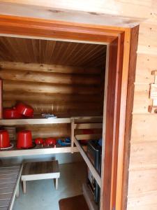 a cabinet with red pots and pans in a cabin at Villa Tammukka in Inari