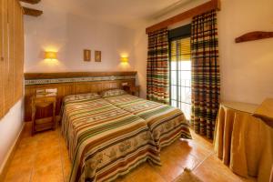 a bedroom with a bed and a desk and a window at Apartamentos El Roqueo in Conil de la Frontera