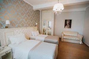 a bedroom with two beds and a chair and a chandelier at Vila Cornelia in Bucharest