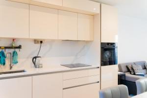 a kitchen with white cabinets and a blue chair at Modern Entire Unit 3BR, 3BA, balcony, 86inch TV - 15mins to city in Romford