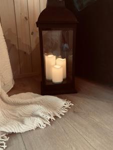 a candle in a glass lantern with a white rug at Aurora Resort in Stasiūnai