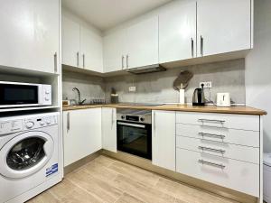 a kitchen with white cabinets and a washer and dryer at Casa do Perestrelo - Guest House in Machico +10 photos