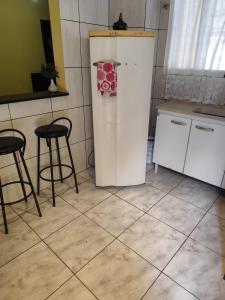 a white refrigerator in a kitchen with two stools at Família Durães Kitnets01 in Londrina +7 photos