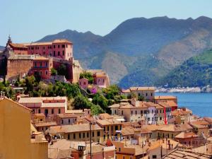 a group of buildings on a hill next to the water at Albergo Ape Elbana in Portoferraio