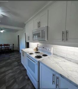 a white kitchen with a stove and a microwave at Jeans Place A Hot tub Oasis in Lewisporte