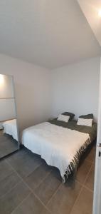 a bedroom with a bed with white sheets and a mirror at Appartements cosy et fonctionnels in Villeneuve-le-Roi