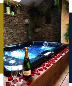 a hot tub with a bottle of wine and wine glasses at Hébergement insolite avec jacuzzi privatif Millau in Millau