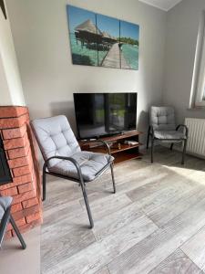 salon z telewizorem i krzesłem w obiekcie Brzask w mieście Mosty