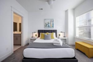 a white bedroom with a large bed with yellow pillows at Double Townhomes Elegant Design Big Groups in Nashville