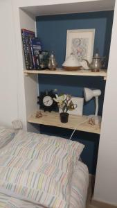 a bedroom with a bed and a shelf with a clock at Le Nid, petit studio cosy et central in Besançon