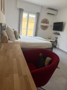 a bedroom with a bed and a red chair at Bas de Villa à 15 min de Nice avec piscine in Carros +6 photos