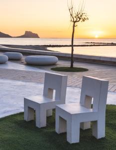 two white chairs and a tree on the beach at Altea Beach in Altea