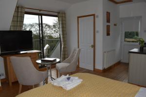a living room with a television and a table and chairs at Frogwell in Strete