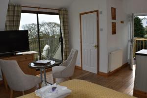 a living room with a television and a table and chairs at Frogwell in Strete