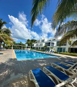 a resort swimming pool with lounge chairs and palm trees at Villas del Mar PTY in Río Hato