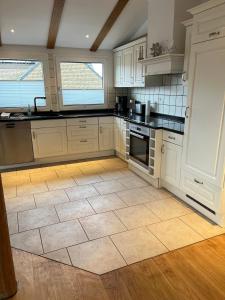 a kitchen with white cabinets and a tile floor at Lerchennest Nottuln in Nottuln +8 photos